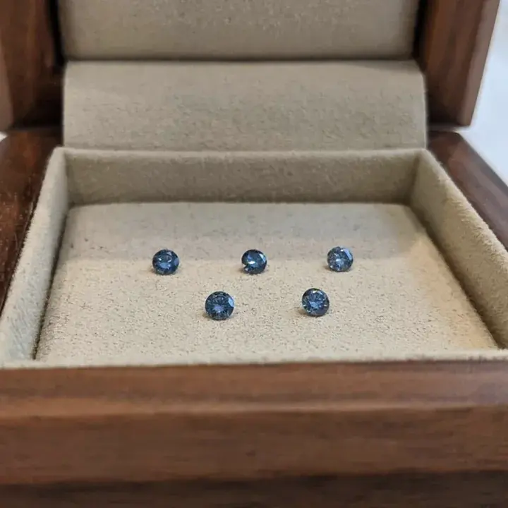Several small diamonds set in a cream-lined wooden box
