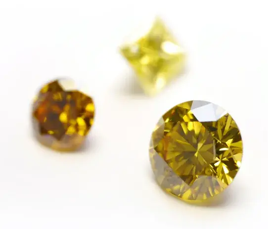 Yellow and amber Semper Fides diamonds on a white surface