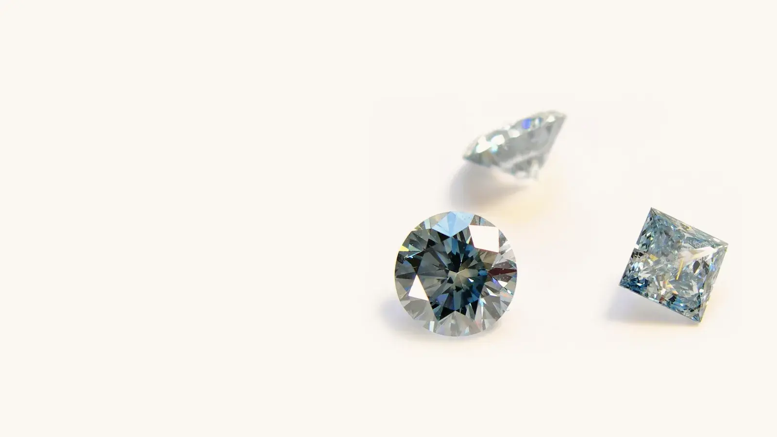 Three Semper Fides diamonds in blue and white tones on a white surface